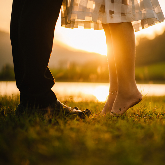 couples legs in field at sunset